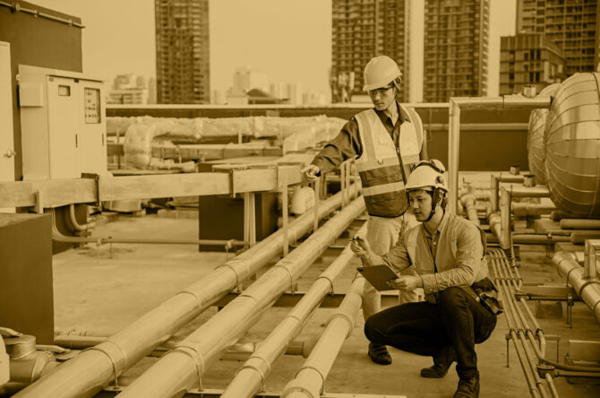 Asian man engineer holding tablet working at rooftop building construction. Male technician worker working checking hvac of office building. Engineering installing large air conditioning system.