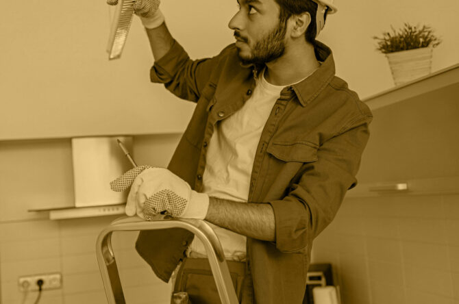 Electrician worker is installing electric lamps light in kitchen. Construction decoration concept